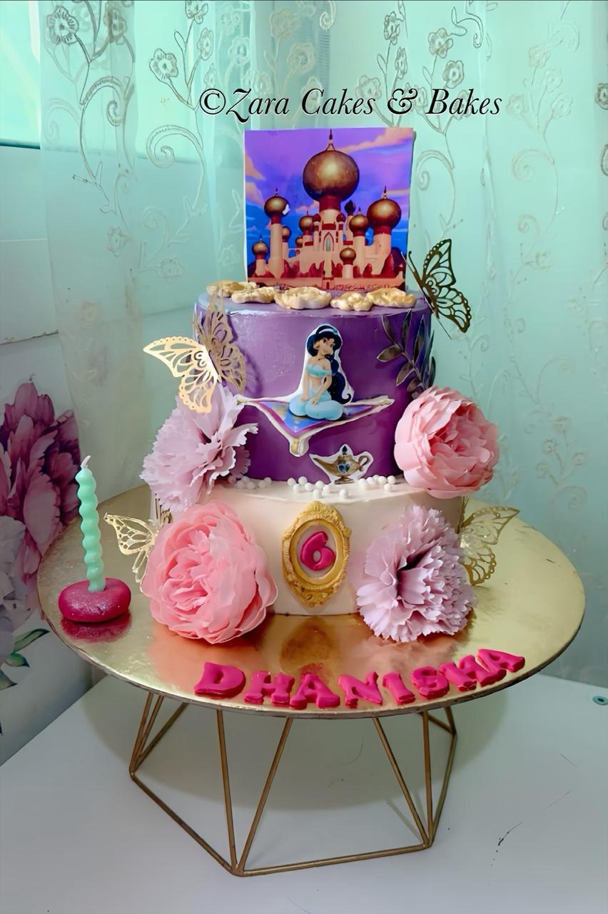 Two-tier Princess Jasmine birthday cake with purple fondant, pink flowers, gold butterflies, and Agrabah topper