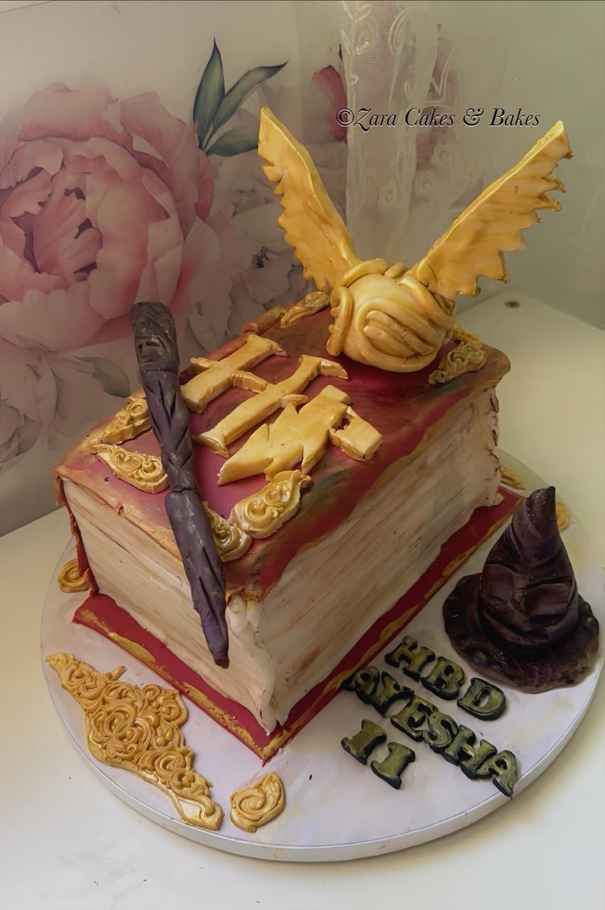 Harry Potter book shaped cake with golden snitch, magic wand and sorting hat topper