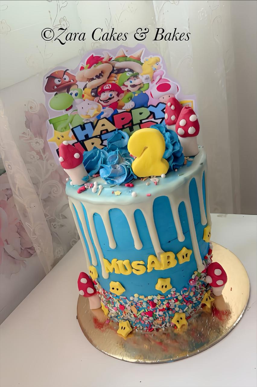 Blue Super Mario birthday cake with white chocolate drip, fondant mushrooms, and character topper for a 2nd birthday.