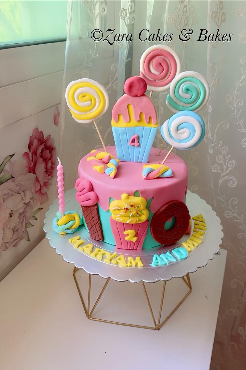 Colorful candy-themed birthday cake with fondant lollipops, cupcakes, and donut decorations for kids party