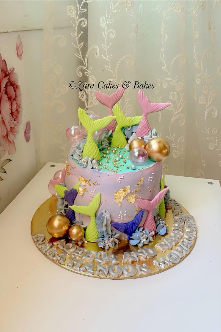 Pastel purple mermaid birthday cake with fondant tails, gold leaf, and edible pearls for kids party