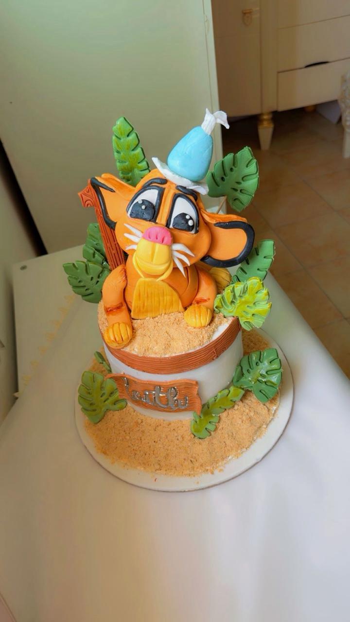 Timon Lion King character cake with jungle leaves and blue hat for birthday