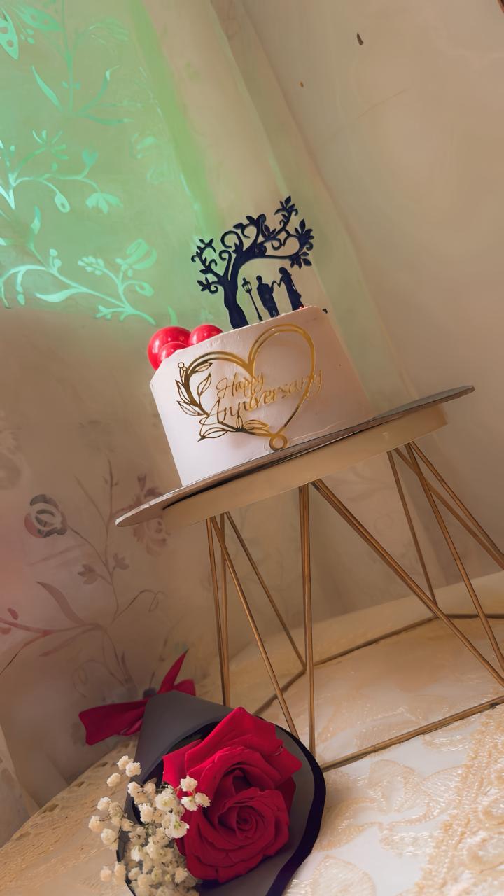 Elegant white anniversary cake with golden heart topper and couple silhouette from Zara Cakes Riyadh
