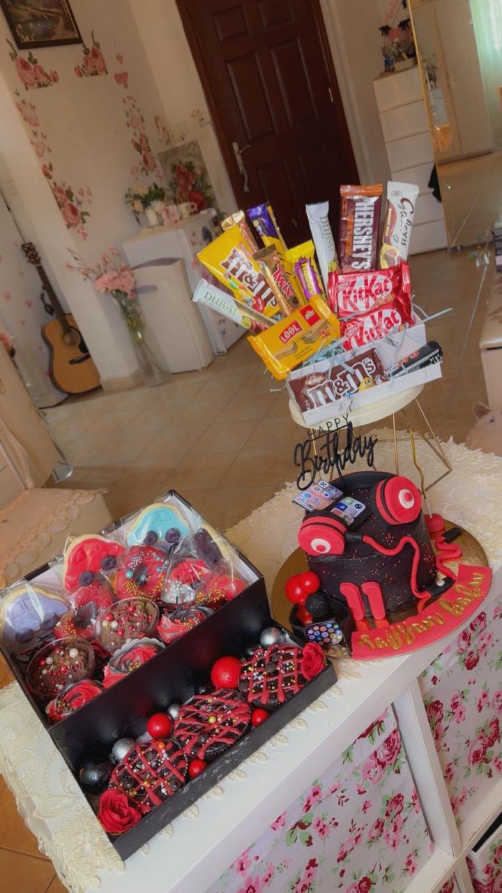 Gaming themed birthday cake with red headphones, chocolate bouquet, and strawberry dessert box from Zara Cakes Riyadh