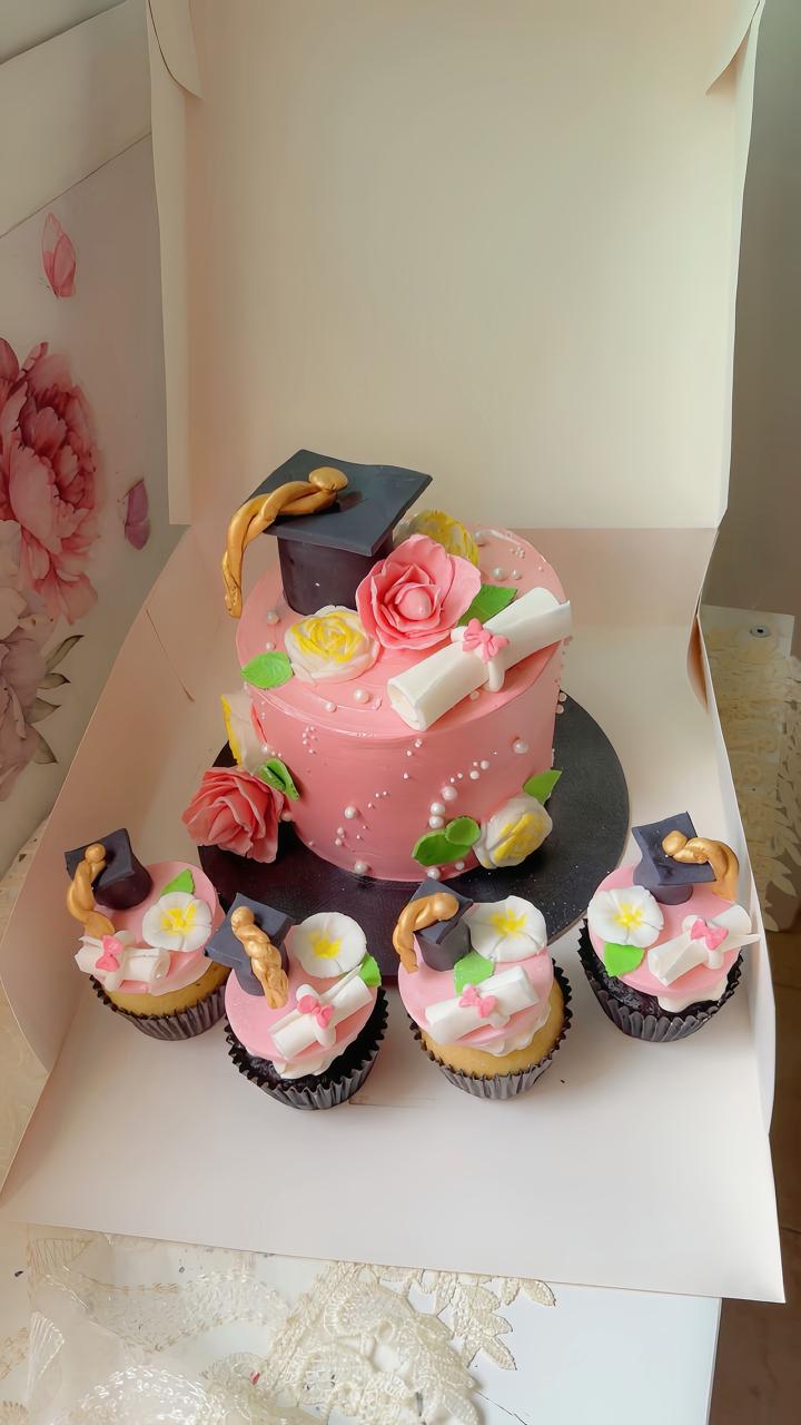 Elegant pink graduation cake with floral decorations and matching cupcakes from Zara Cakes Riyadh