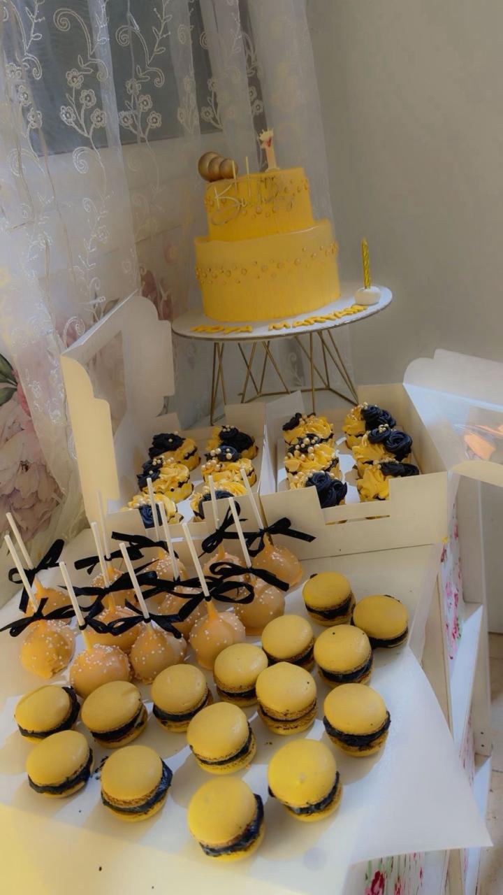 Luxurious yellow and black themed birthday dessert table with cake and macarons from Zara Cakes Riyadh