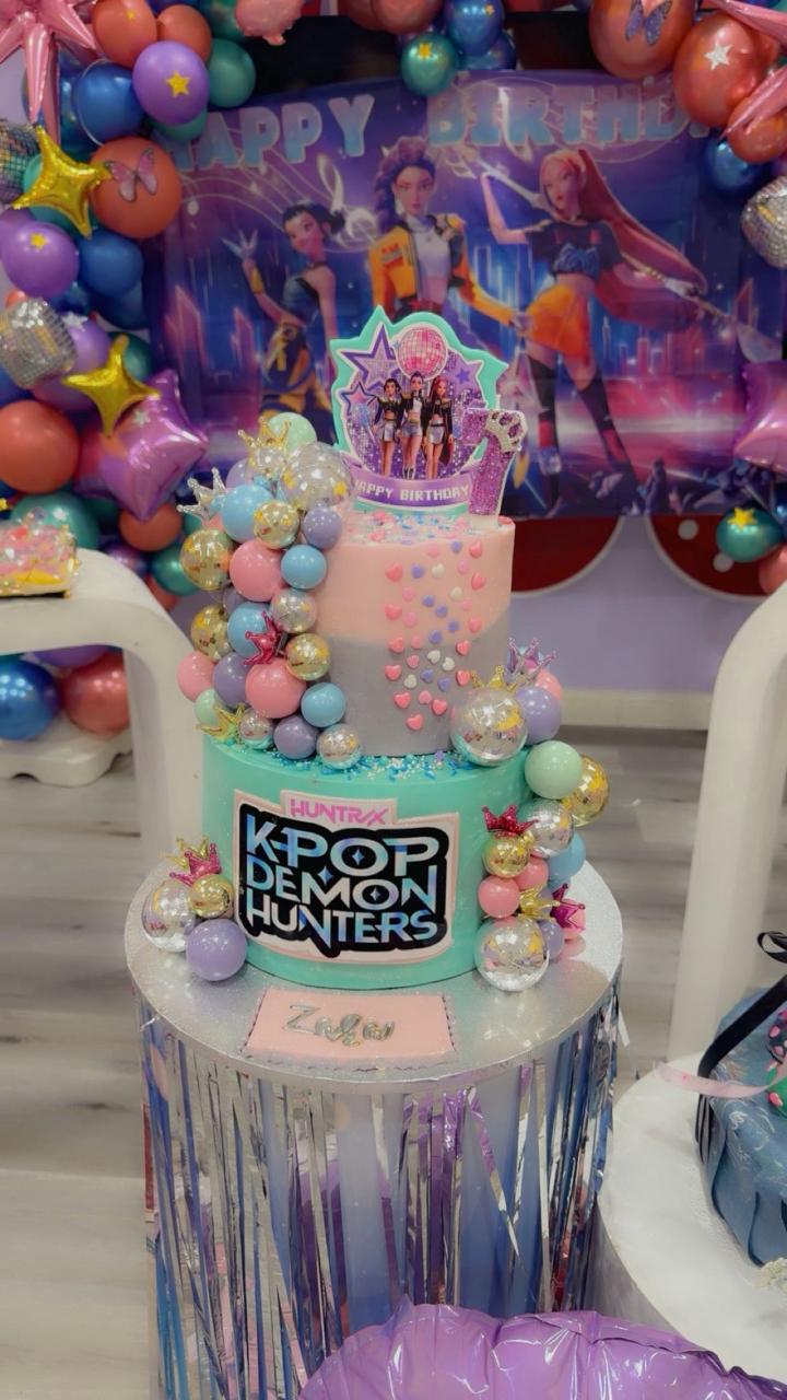 Colorful K-Pop Demon Hunters birthday cake with balloons and character topper from Zara Cakes