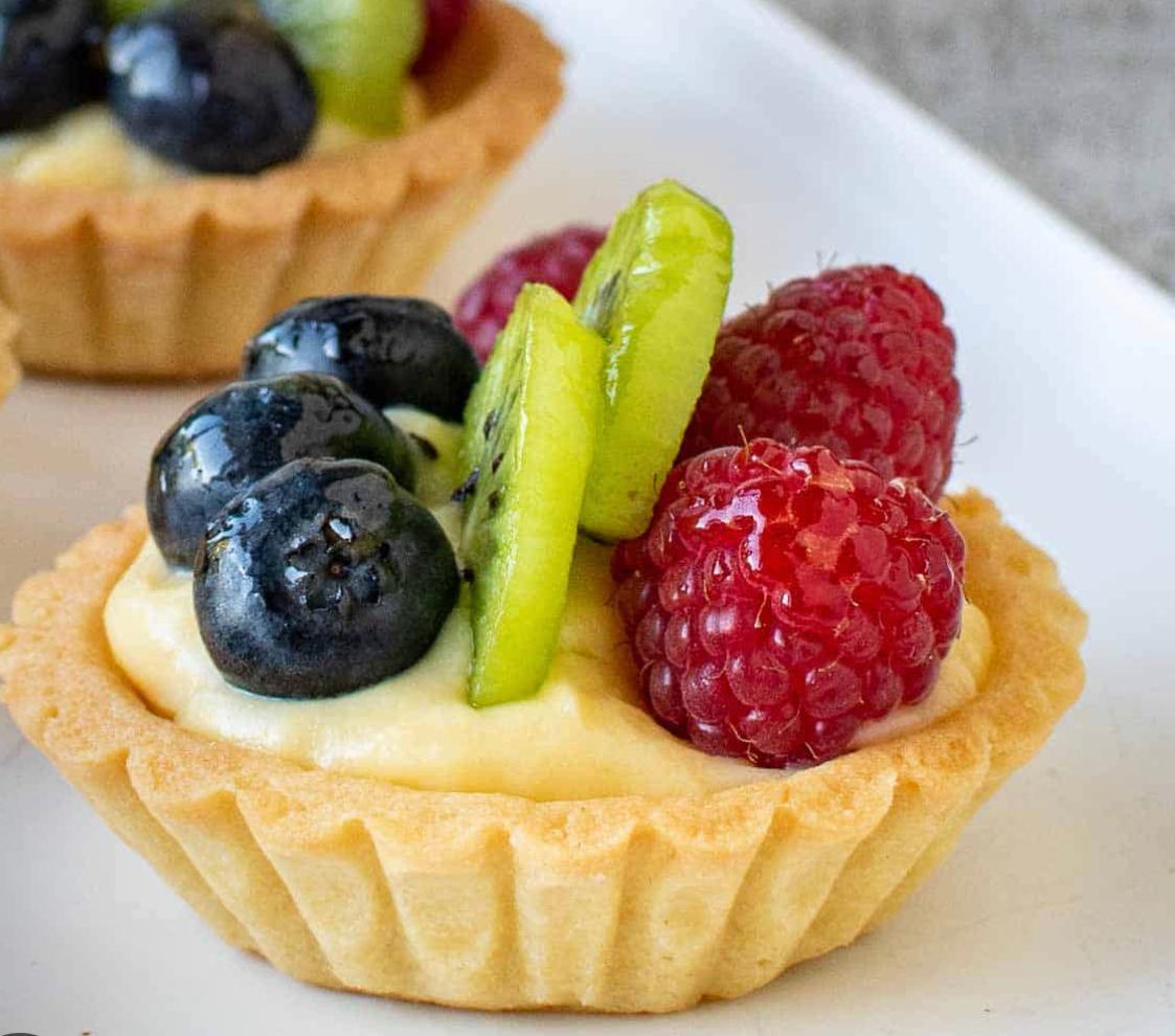 Mini fruit tartlets topped with fresh berries and kiwi from Zara Cakes Riyadh bakery