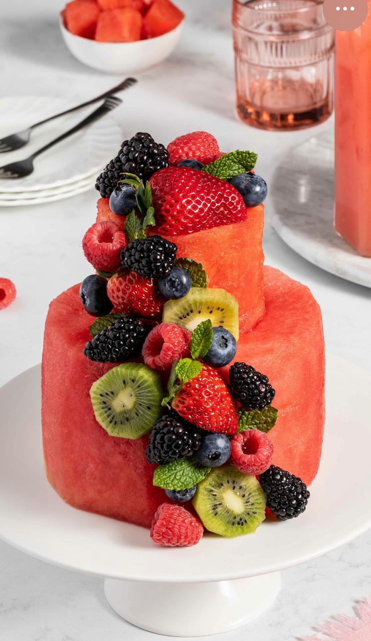 Two-tiered fresh watermelon cake decorated with mixed berries and kiwi slices for a healthy dessert